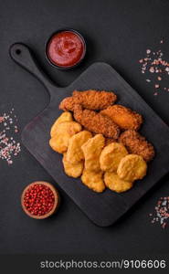 Delicious crispy chicken nuggets with salt and spices on a dark concrete background. Junk food, fast food