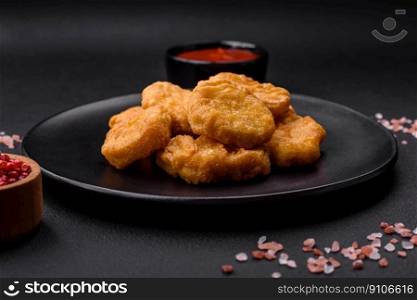 Delicious crispy chicken nuggets with salt and spices on a dark concrete background. Junk food, fast food