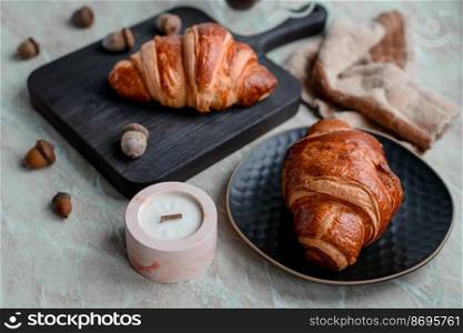Delicious crispy croissant with chocolate with a cup of invigorating coffee on a light concrete background. Delicious nutritious breakfast