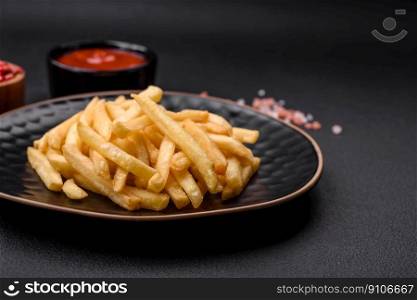Delicious crispy french fries with sa<and sπces on a dark concrete background. Unhea<hy food, fast food