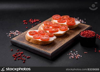 Delicious crispy grilled toast with cheese and cherry tomatoes on a dark concrete background