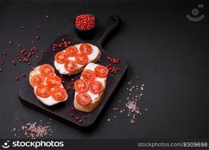 Delicious crispy grilled toast with cheese and cherry tomatoes on a dark concrete background