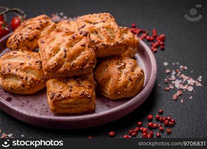 Delicious crispy mini puffs with sausa≥or meat with sa<, thyme and sesame on a dark concrete background