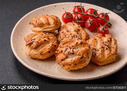 Delicious crispy mini puffs with sausage or meat with salt, thyme and sesame on a dark concrete background