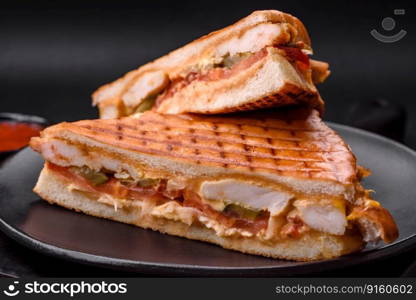 Delicious crispy sandwich with chicken breast, tomatoes, ketchup and spices on a dark concrete background