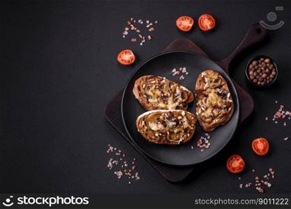 Delicious crispy toast or bruschetta with fried onion, ch&ignon mushrooms and cheese with spices and herbs on a dark concrete background