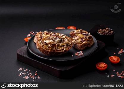 Delicious crispy toast or bruschetta with fried onion, champignon mushrooms and cheese with spices and herbs on a dark concrete background