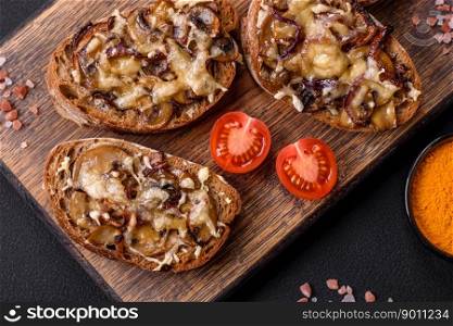 Delicious crispy toast or bruschetta with fried onion, champignon mushrooms and cheese with spices and herbs on a dark concrete background