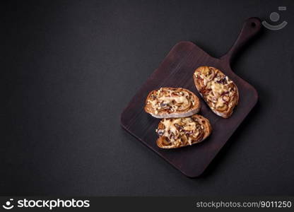 Delicious crispy toast or bruschetta with fried onion, champignon mushrooms and cheese with spices and herbs on a dark concrete background