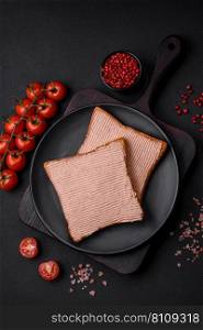 Delicious crispy toast with chicken or goose pate with salt and spices on a dark concrete background
