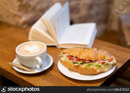 delicious croissant with coffee and a book on the table