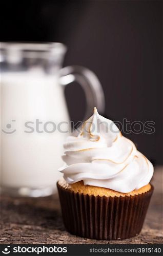 Delicious cupcakes with a carafe of milk on wooden table. Delicious cupcakes with a carafe of milk