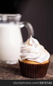 Delicious cupcakes with a carafe of milk on wooden table. Delicious cupcakes with a carafe of milk