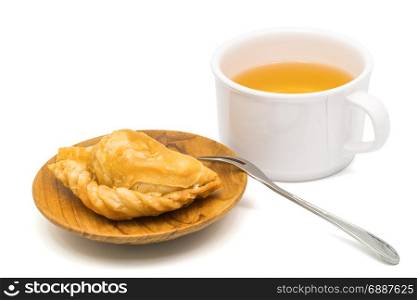 Delicious Curry Puff in a wooden plate and a cup of tea on white background