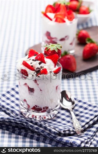 delicious dessert glasses with strawberries and cream on traditional home towel