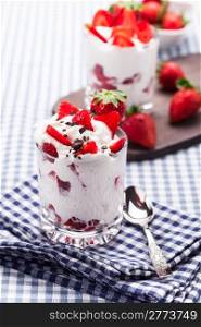 delicious dessert glasses with strawberries and cream on traditional home towel