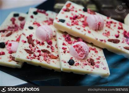 delicious dessert white chocolate bar decorated with pink chocolate ball and raisins, selective focus.. delicious dessert white chocolate bar decorated with pink chocolate ball and raisins, selective focus
