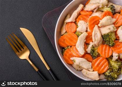 Delicious dish consisting of pieces of boiled chicken, broccoli and carrots with spices and herbs on a dark concrete background