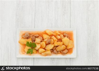 Delicious dish of cooked potatoes with meat on gray wooden background
