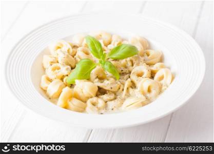 Delicious dish of tortellini with pesto in white plate. Tortellini with pesto