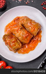 Delicious dolma in tomato sauce with carrots, onions, salt, spices and herbs on a dark concrete background