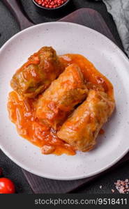 Delicious dolma in tomato sauce with carrots, onions, salt, spices and herbs on a dark concrete background