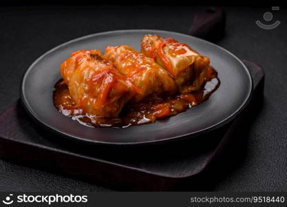 Delicious dolma in tomato sauce with carrots, onions, salt, spices and herbs on a dark concrete background