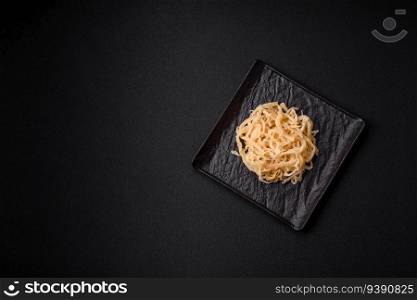 Delicious dried squid in the form of shavings with salt and spices on a ceramic plate on a dark concrete background