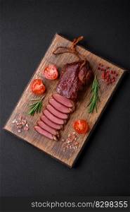 Delicious duck fillet or breast grilled or smoked with spices and salt on a dark concrete background