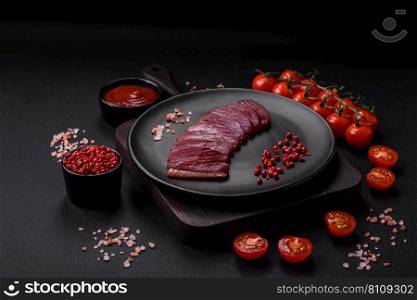 Delicious duck fillet smoked or grilled with spices and salt on a dark concrete background