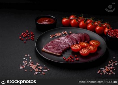 Delicious duck fillet smoked or grilled with spices and salt on a dark concrete background