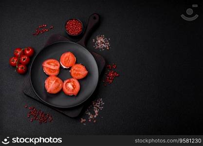 Delicious eggplant cut into circles grilled and cooked with mayonnaise and tomatoes on a dark concrete background