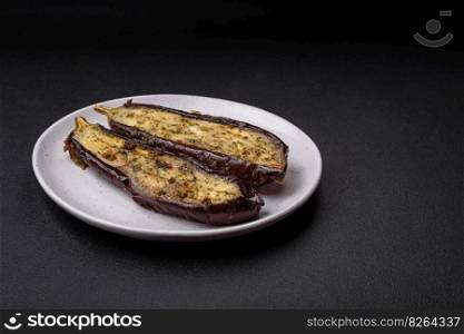 Delicious eggplant cut into two halves baked with salt, spices and herbs on a dark concrete background
