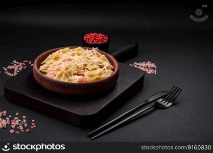 Delicious farfalle pasta with langoustine shrimp with creamy sauce and cheese on a dark concrete background