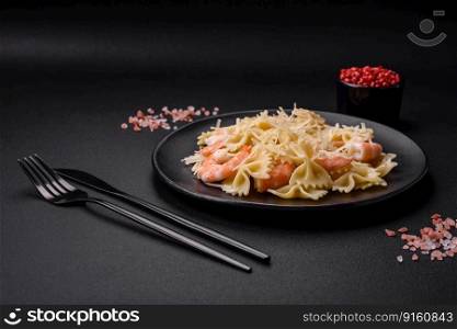 Delicious farfalle pasta with langoustine shrimp with creamy sauce and cheese on a dark concrete background