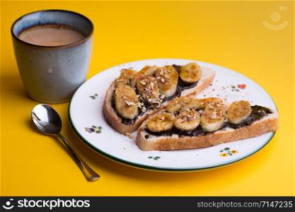 delicious french breakfast - toast with chocolate and fried bananas on yellow background
