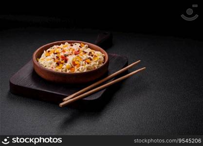 Delicious fresh Asian noodles with pieces of vegetables, meat, with salt, spices and herbs on a dark concrete background