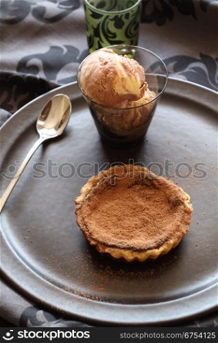 Delicious fresh baked chocolate tart with a caramel ice cream sprinkled with cocoa.