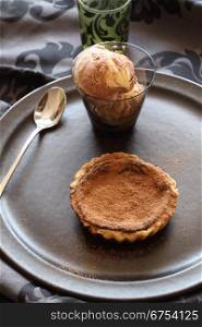Delicious fresh baked chocolate tart with a caramel ice cream sprinkled with cocoa.