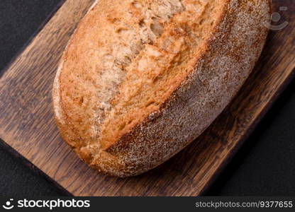 Delicious fresh baked crispy loaf of bread with seeds and grains on a dark concrete background
