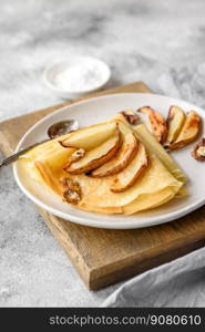 Delicious fresh baked pancakes with honey and fruits on a textured concrete background. Useful healthy food