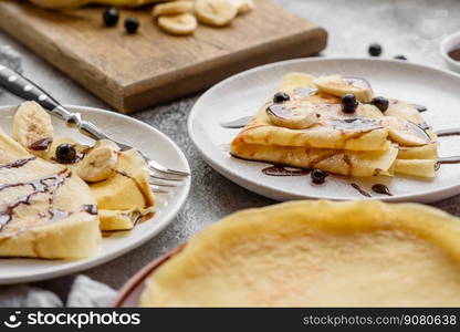 Delicious fresh baked pancakes with honey and fruits on a textured concrete background. Useful healthy food