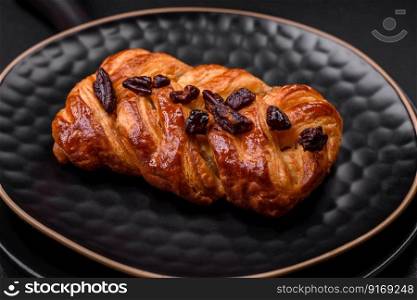 Delicious fresh baked pigtail bun with nuts and syrup on a dark concrete background