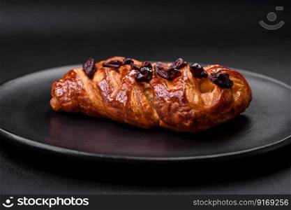 Delicious fresh baked pigtail bun with nuts and syrup on a dark concrete background