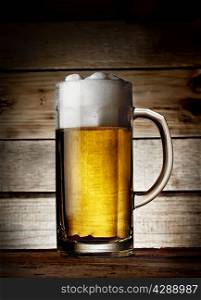 Delicious fresh beer mug on the wooden background