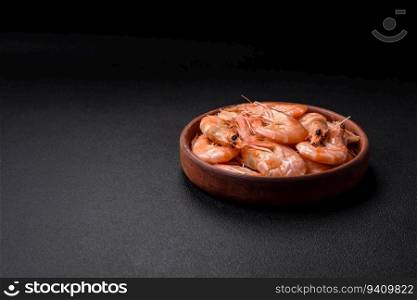 Delicious fresh boiled tiger prawns with salt and spices on a ceramic plate on a dark concrete background