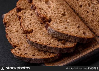 Delicious fresh brown sourdough bread with grains on dark concrete background