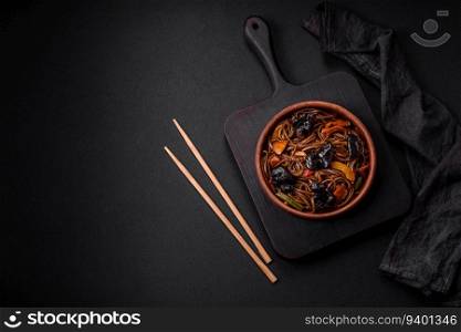 Delicious fresh buckwheat noodles or udon with mushrooms, peppers and other vegetables, spices and herbs on a dark concrete background