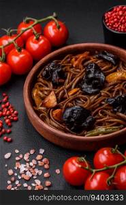 Delicious fresh buckwheat noodles or udon with mushrooms, peppers and other vegetables, spices and herbs on a dark concrete background