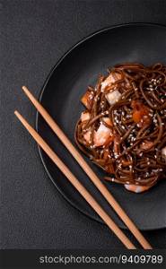 Delicious fresh buckwheat noodles with boiled tiger prawns, salt, spices and mushrooms on a dark concrete background